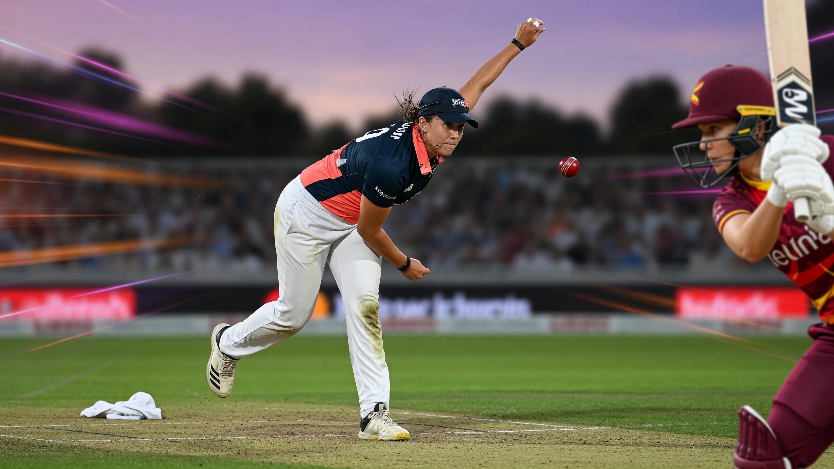 Close sideline action of a batter in coloured kit driving through the off side with shallow depth of field